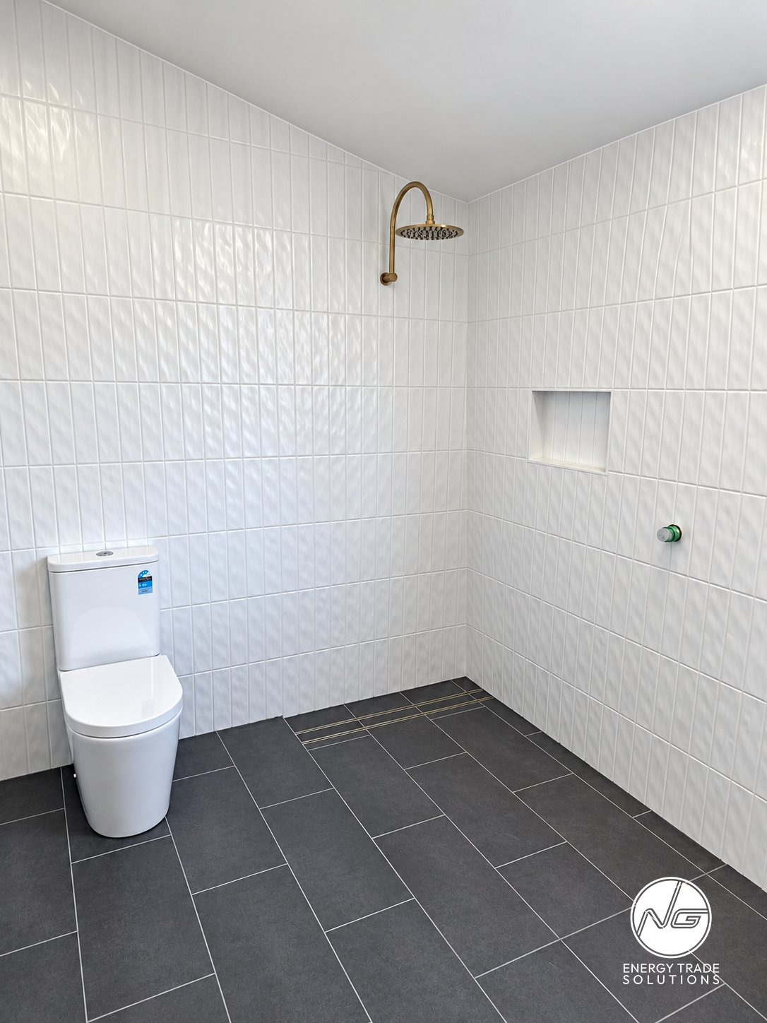 Bathroom plumbing project showing a toilet and shower area during fit-out.