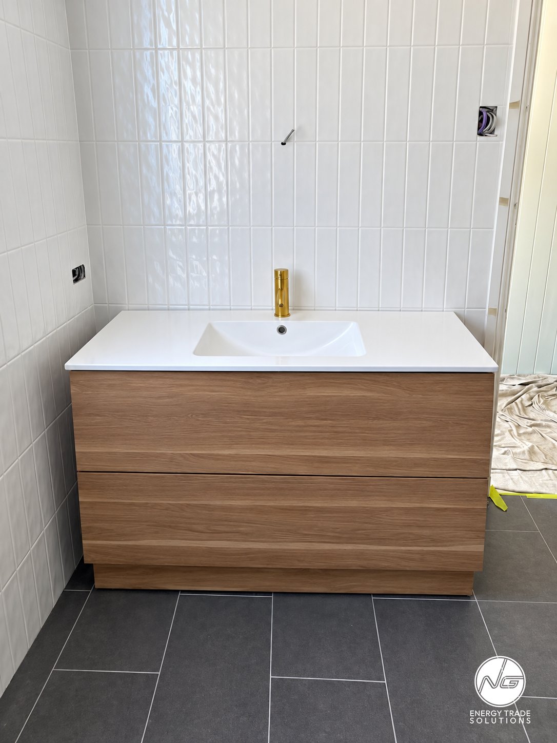 Bathroom vanity and basin with a brass-coloured mixer tap during fit-out.