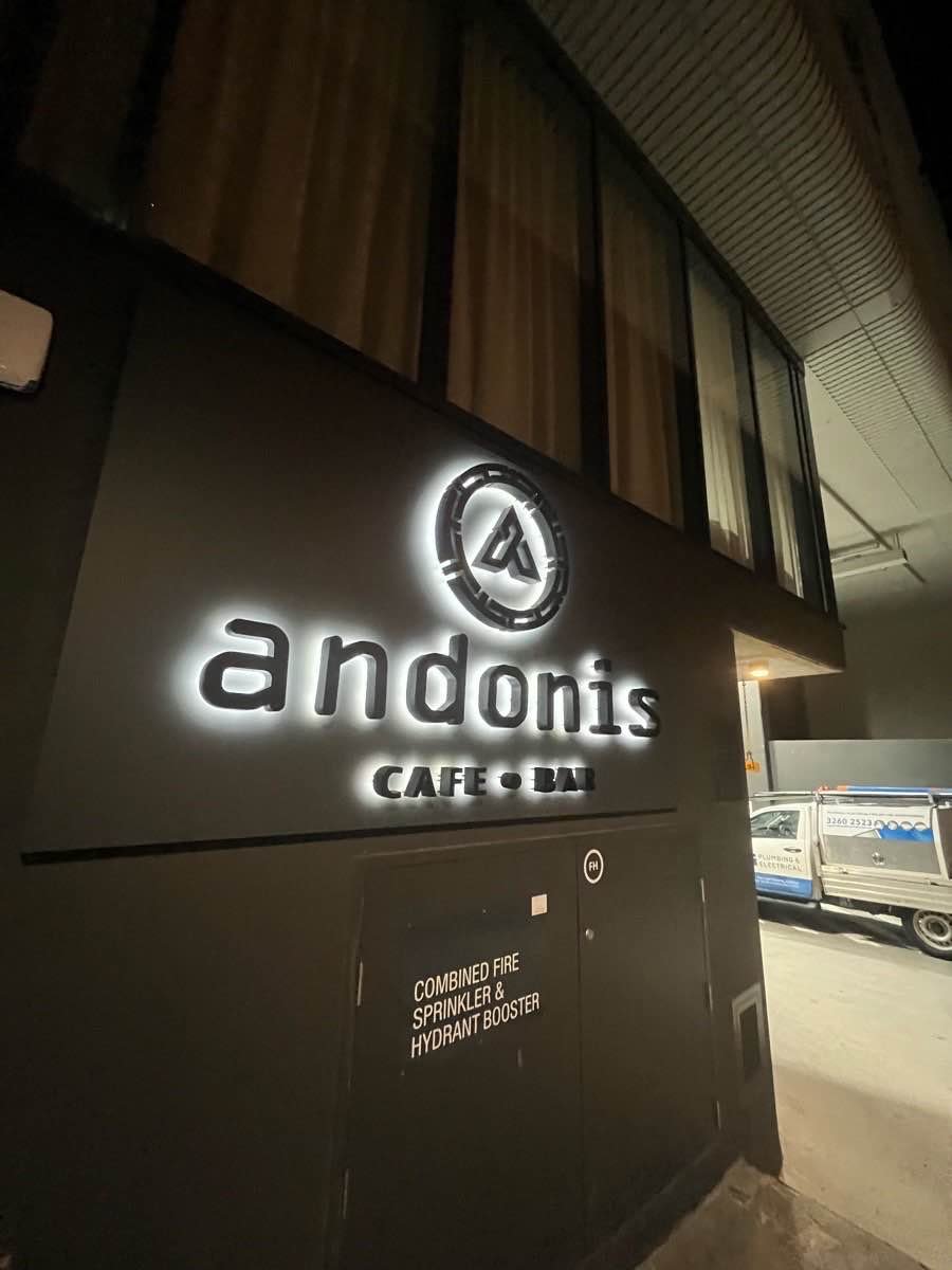 Illuminated Andonis Café signage with an NG service vehicle alongside the building.
