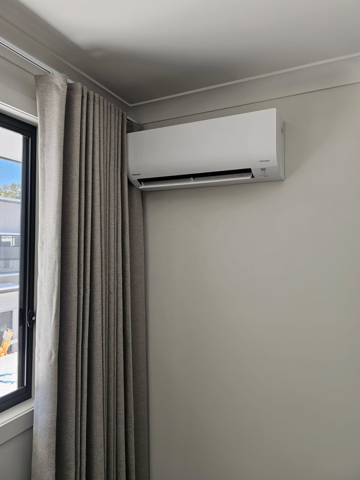 Daikin wall-mounted split-system air conditioner beside a window.