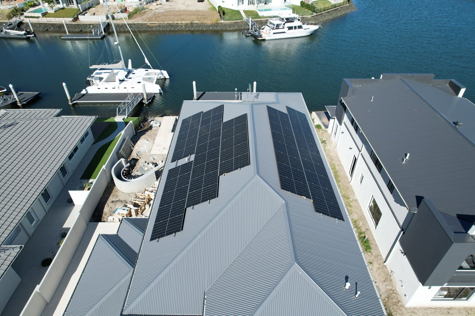 Aerial view of rooftop solar panels on a waterfront home.